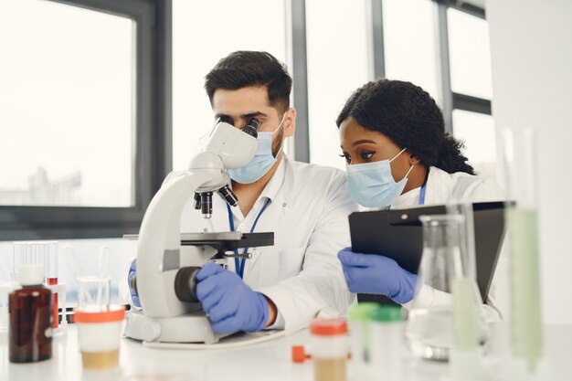 Nueva prueba. Investigadores calificados concentrados vistiendo uniforme. Haciendo prueba, creando vacuna.