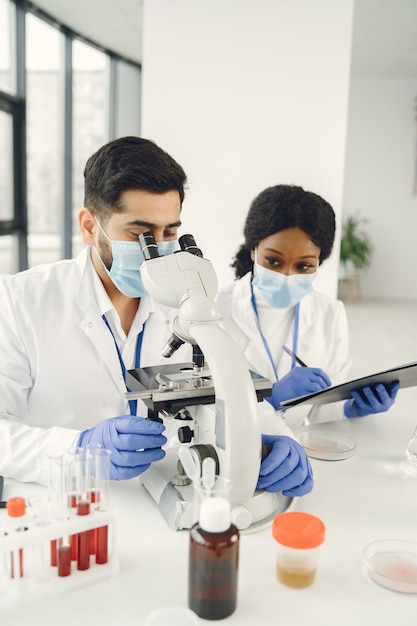 Nueva prueba. Investigadores calificados concentrados vistiendo uniforme. Haciendo prueba, creando vacuna.