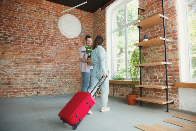 Nueva vida. Pareja joven se mudó a una nueva casa o apartamento. Luce feliz y confiado. Familia, mudanza, relaciones, primer concepto de hogar. Desempacando cajas con sus plantas, libros, poniendo cosas en los estantes.