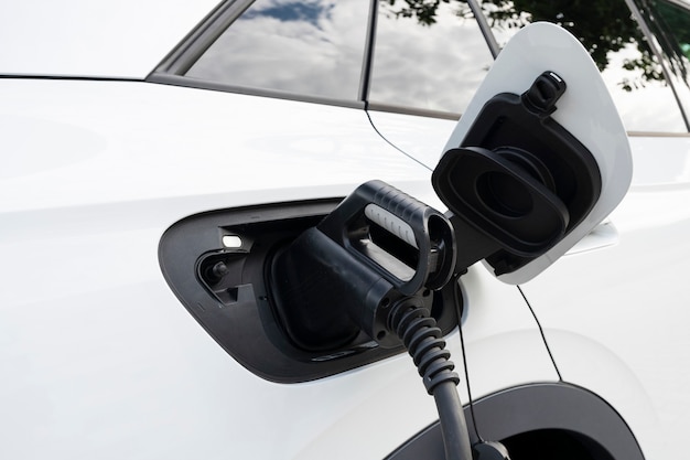 Nuevo coche eléctrico blanco cargando en una estación