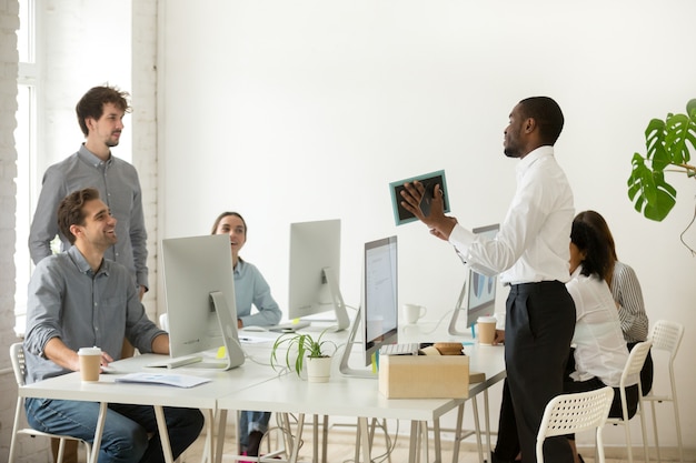 Nuevo empleado africano desempaquetado hablando en la primera oficina, día laborable