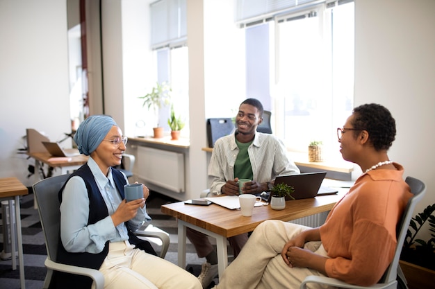 Foto gratuita nuevo empleado masculino conversando con colegas femeninas en su nuevo trabajo de oficina