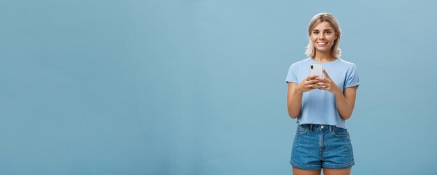 Foto gratuita el nuevo teléfono es un retrato fantástico de una joven rubia moderna y satisfecha con trajes de moda.