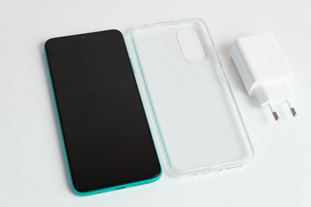 Nuevo teléfono móvil y cargador con tapa transparente sobre fondo blanco aislado