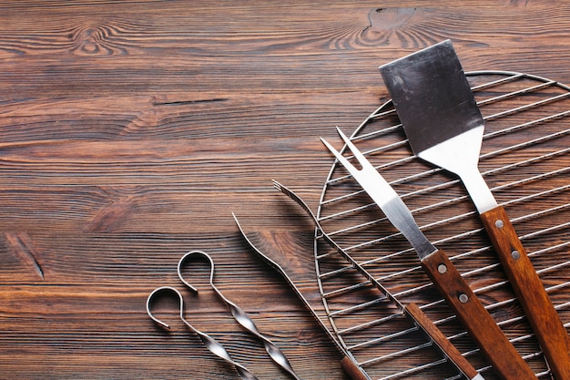 Nuevos utensilios metálicos de barbacoa sobre fondo de madera.