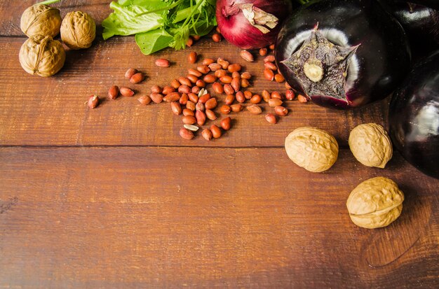 Nuez; Cacahuetes y verduras sobre fondo con textura de madera marrón