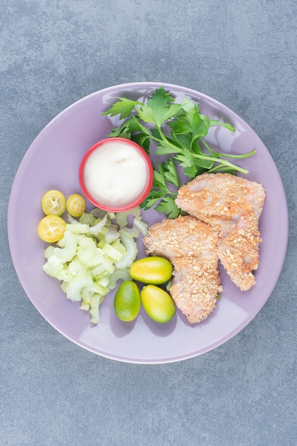 Foto gratuita nuggets de alitas de pollo crudas en un plato morado.