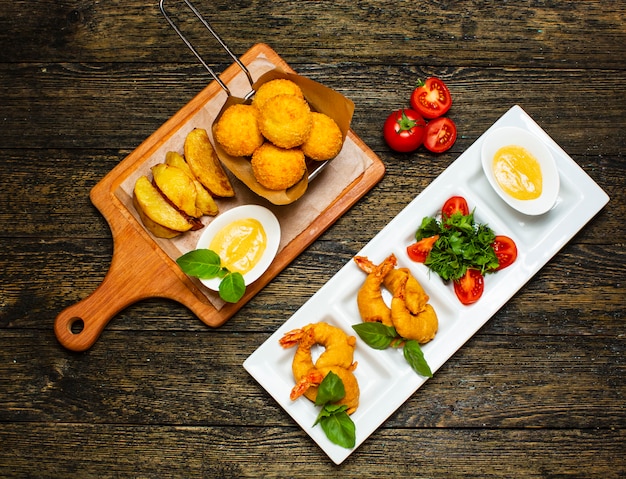 Nuggets fritos y papas con rodajas de huevo y tomate.