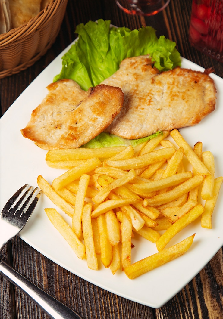 Foto gratuito nuggets de pecho de pollo asado con papas fritas en un plato blanco