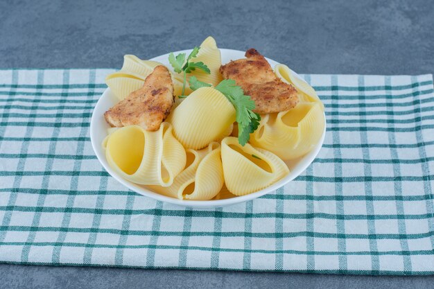 Nuggets de pollo asado y pasta hervida en un tazón blanco.