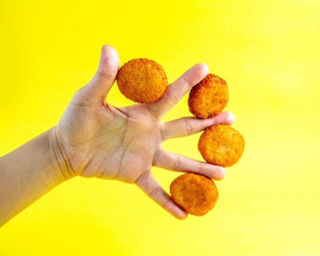 Nuggets de pollo entre los dedos del hombre vista lateral