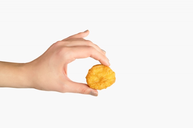 Nuggets de pollo frito en mano femenina sobre fondo blanco.