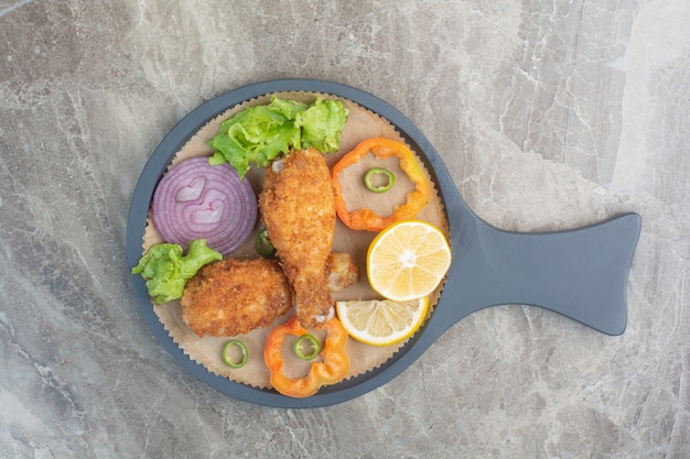 Nuggets de pollo con limón y cebolla en sartén oscura