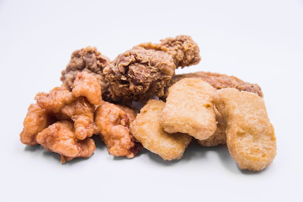 Nuggets de pollo; muslo de pollo frito y palomitas de maíz crujientes aisladas sobre fondo blanco