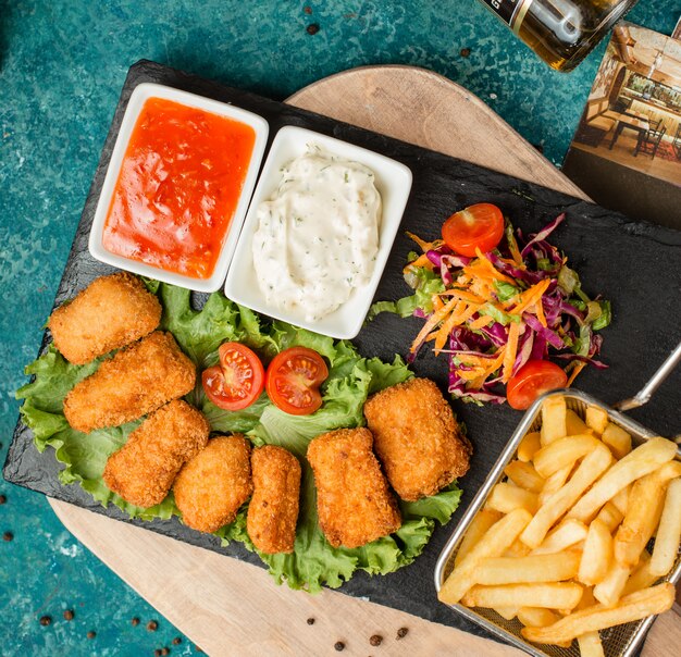 Nuggets de pollo con papas fritas, ensalada y salsa de tomate