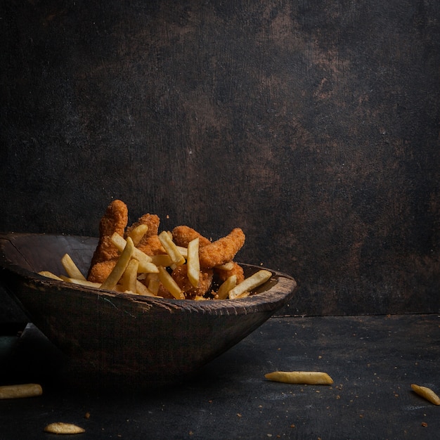 nuggets de pollo con papas fritas en placa de madera