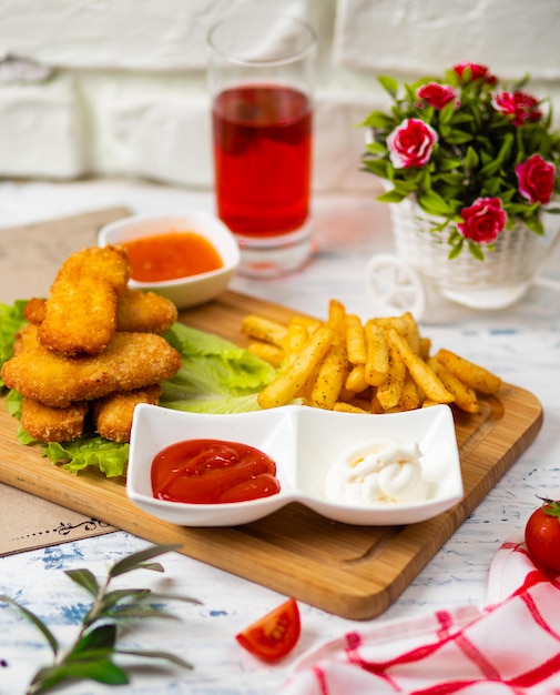 Nuggets de pollo y papas fritas, salsas de salsa de tomate y mayonesa en una cocina