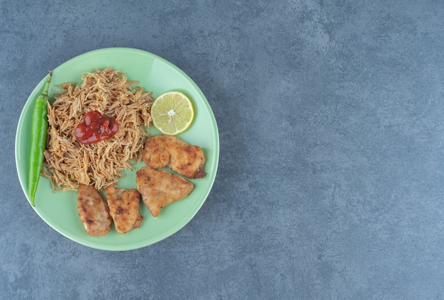 Foto gratuita nuggets de pollo y pasta frita en placa verde.