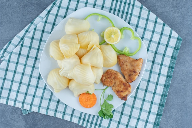 Nuggets de pollo y pasta hervida en un plato blanco.