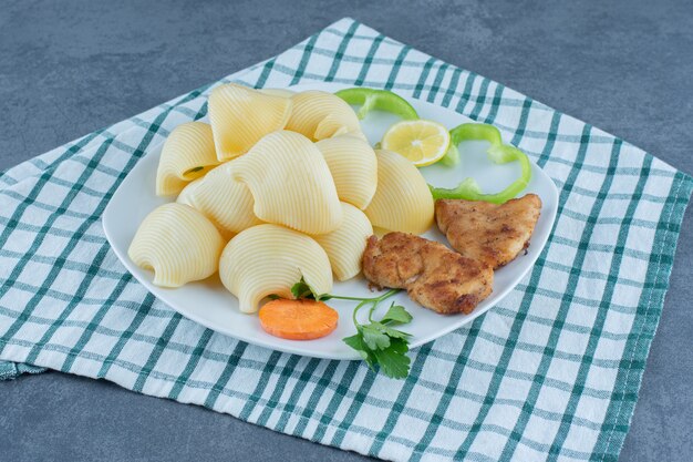 Nuggets de pollo y pasta hervida en un plato blanco.