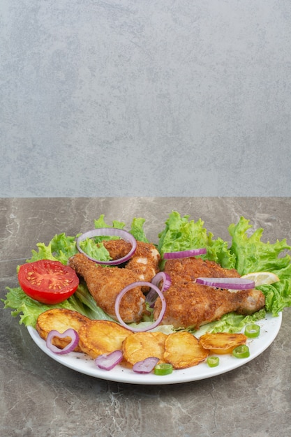 Nuggets de pollo con patatas fritas y cebolla en un plato blanco.