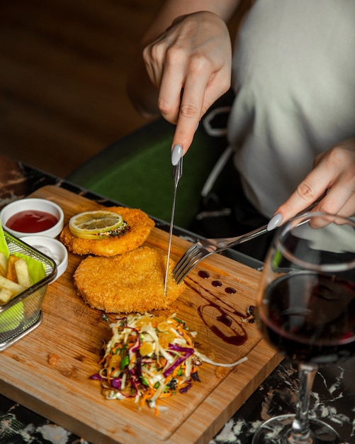 Nuggets de pollo redondo sobre una tabla de madera con sala y vaso de vino tinto.