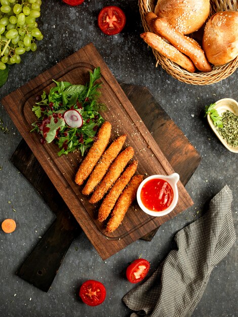 Nuggets de pollo con salsa sobre una plancha de madera