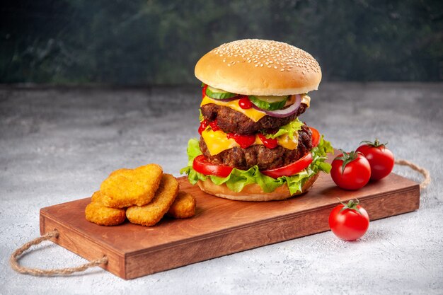 Nuggets de pollo sándwich y tomates sabrosos caseros en la tabla de cortar de madera en la superficie borrosa