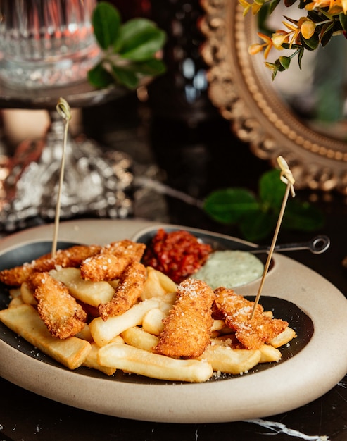 Nuggets de pollo servidos con papas fritas y salsas