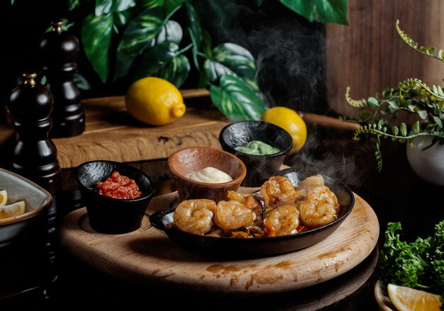 Nuggets de pollo servidos con pesto, crema y salsa de tomate dentro de cerámica negra