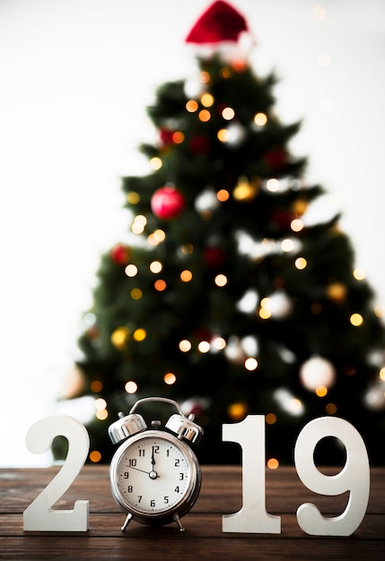 Número de año nuevo en mesa con reloj y abeto