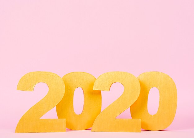 Números de año nuevo 2020 sobre fondo rosa con espacio de copia