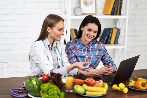 Un nutricionista sonriente aconseja a una paciente joven sobre la nutrición y la dieta adecuadas