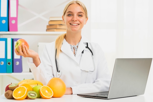 Foto gratuita nutricionista sonriente de tiro medio con manzana