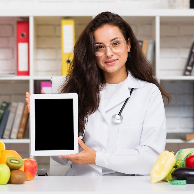 Foto gratuita nutricionista de tiro medio sosteniendo una maqueta de tableta