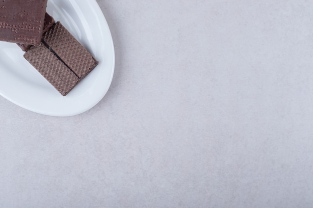 Obleas recubiertas de chocolate en un plato sobre una mesa de mármol.