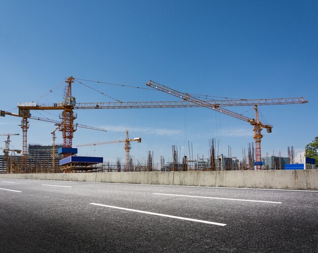 Obras de construcción con grúas contra el cielo azul