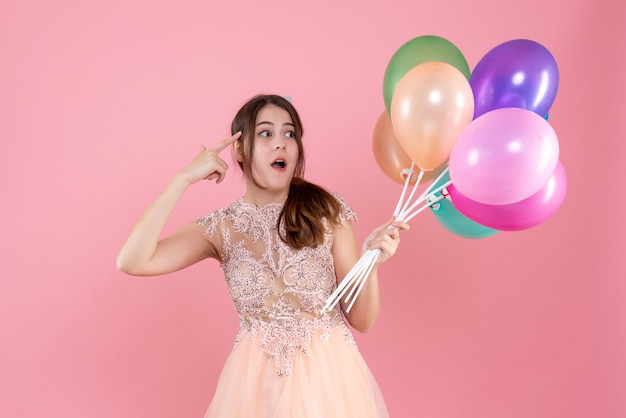 Foto gratuita observando a la fiestera con gorra de fiesta sosteniendo globos en rosa