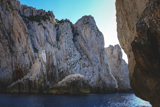 Océano rodeado por acantilados rocosos que brillan bajo el cielo azul - ideal para fondos de pantalla