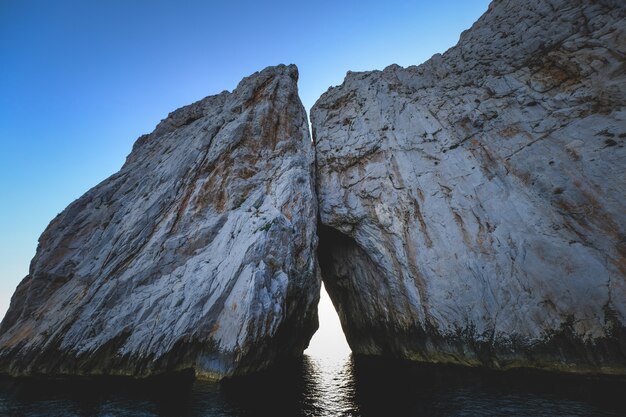 Océano rodeado por acantilados rocosos que brillan bajo el cielo azul - ideal para fondos de pantalla