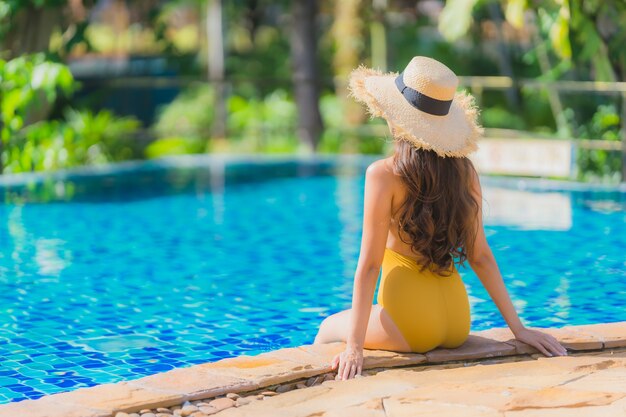 El ocio asiático joven hermoso de la mujer del retrato relaja sonrisa y feliz alrededor de piscina en centro turístico del hotel