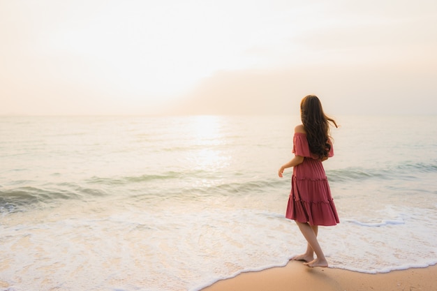 Ocio feliz de la sonrisa de la mujer asiática joven hermosa del retrato en el mar y el océano de la playa