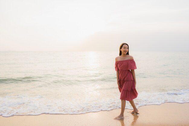 Ocio feliz de la sonrisa de la mujer asiática joven hermosa del retrato en el mar y el océano de la playa