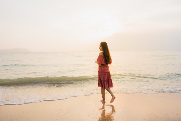 Ocio feliz de la sonrisa de la mujer asiática joven hermosa del retrato en el mar y el océano de la playa