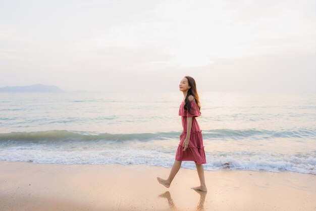 Ocio feliz de la sonrisa de la mujer asiática joven hermosa del retrato en el mar y el océano de la playa