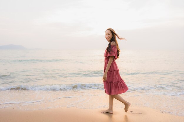 Ocio feliz de la sonrisa de la mujer asiática joven hermosa del retrato en el mar y el océano de la playa