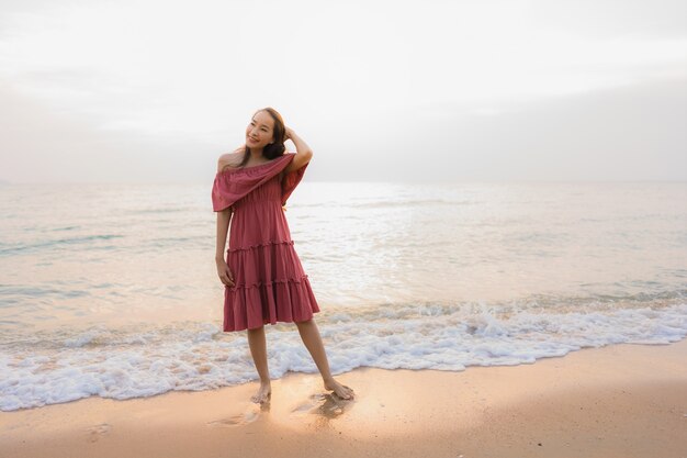 Ocio feliz de la sonrisa de la mujer asiática joven hermosa del retrato en el mar y el océano de la playa