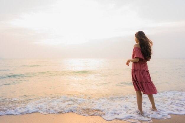 Ocio feliz de la sonrisa de la mujer asiática joven hermosa del retrato en el mar y el océano de la playa