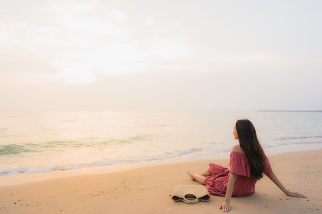 Ocio feliz de la sonrisa de la mujer asiática joven hermosa del retrato en el mar y el océano de la playa