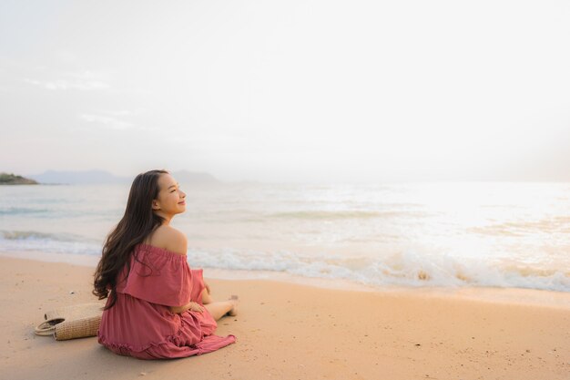Ocio feliz de la sonrisa de la mujer asiática joven hermosa del retrato en el mar y el océano de la playa